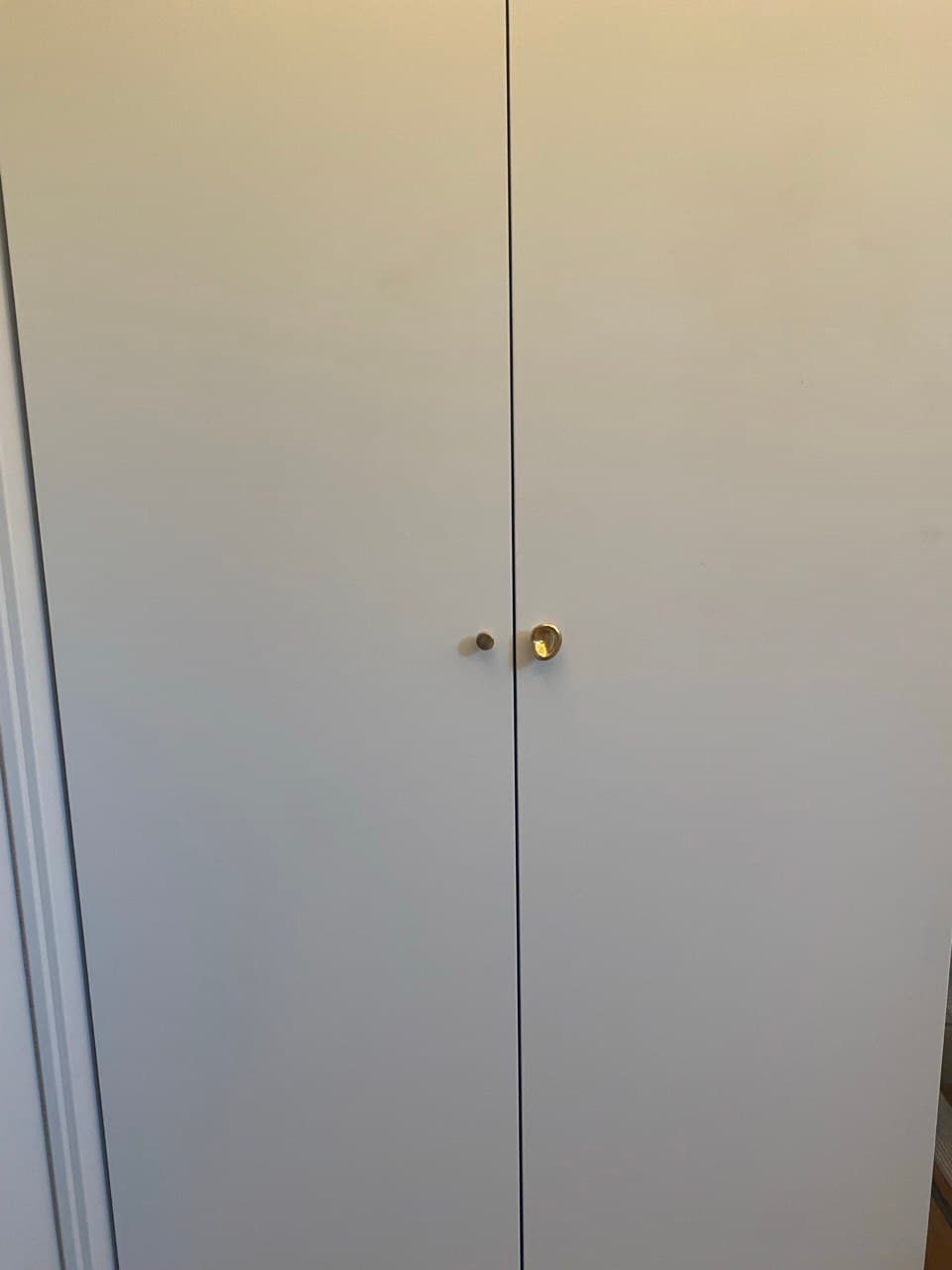 White lacquered wardrobe with brass knobs